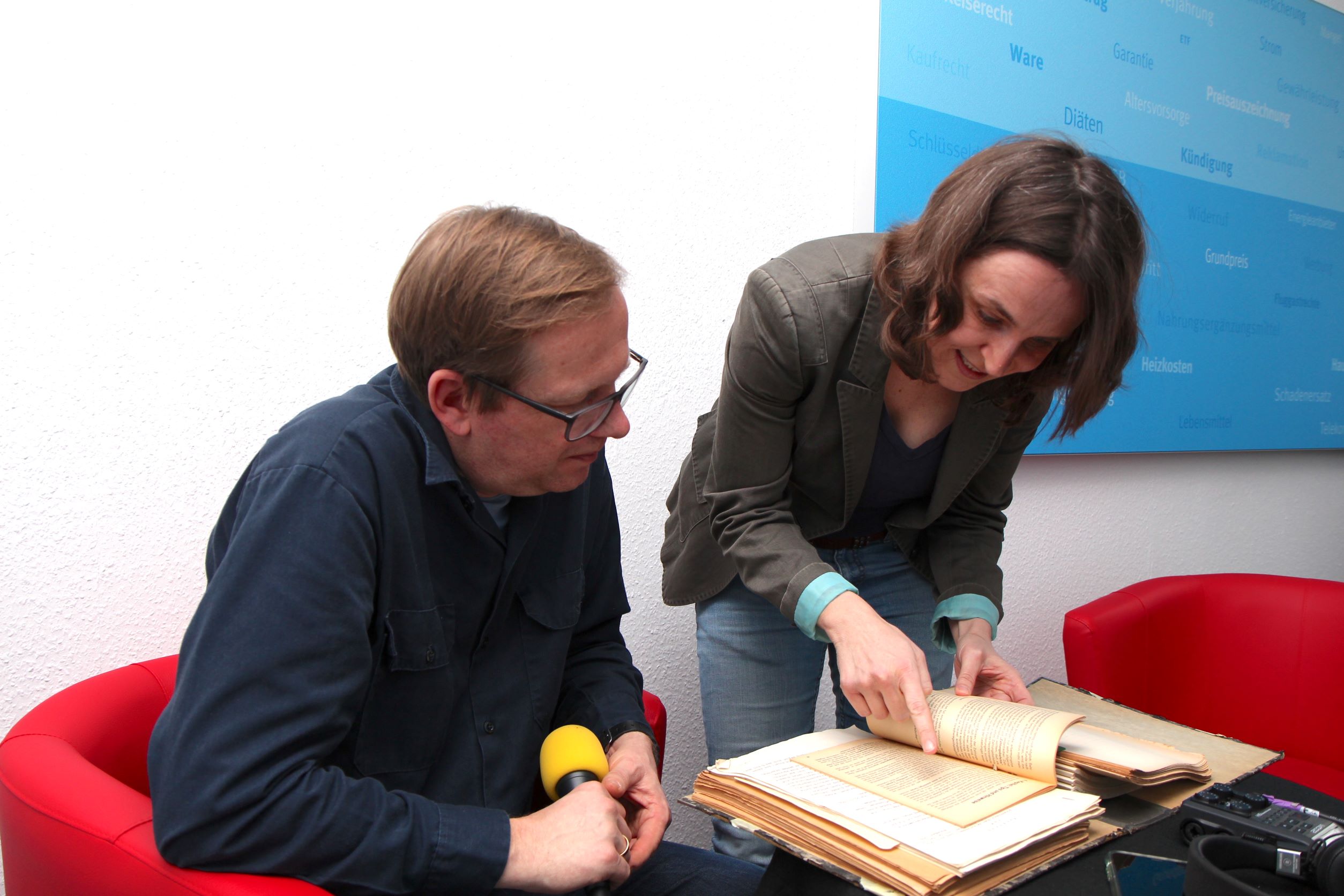 Ein Mann und eine Frau blättern in einem Ordner mit Schwarzbüchern