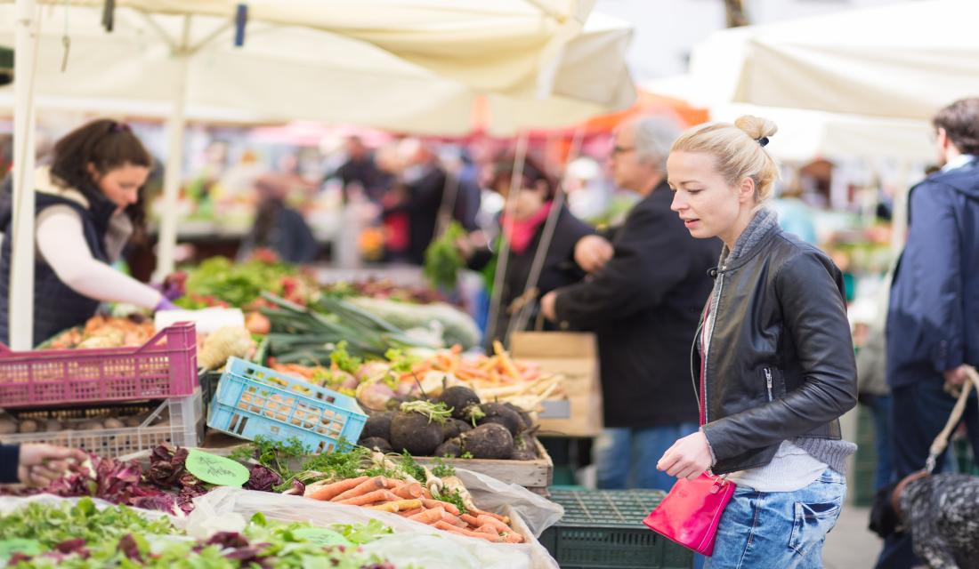 Frau kauft an einem Marktstand ein