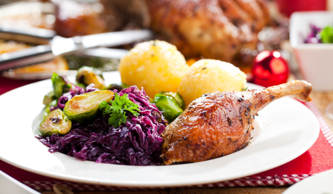 Auf einem Festtagstisch steht ein Teller mit Enten-Keule, Knödeln und Rotkohl