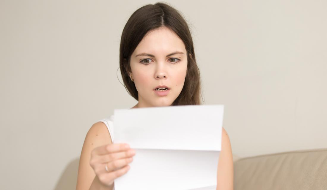 Frau liest erschrocken eine Mahnung.