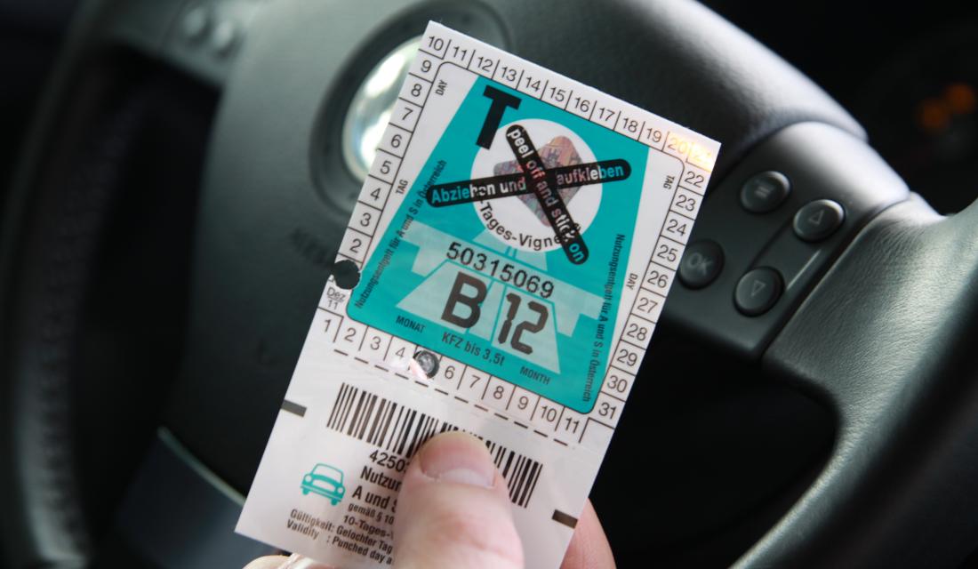 Mensch hält Vignette für Österreichische Autobahn in der Hand