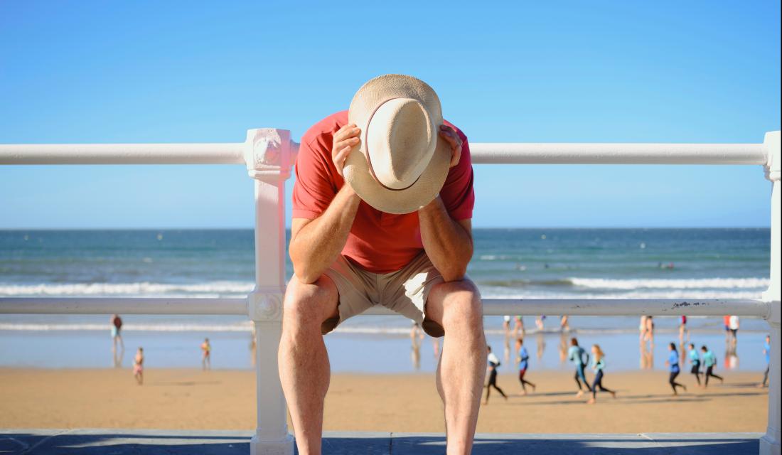 Mann stützt sich den Kopf auf die Hände am Strand