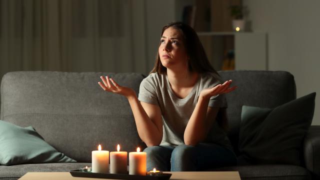 Eine junge Frau sitzt wegen einer Stromsperre bei Kerzenlicht im Dunkeln 