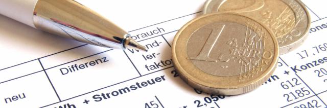 Stift und Münzen liegen auf einer Stromrechnung.