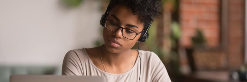Junge Frau sitzt vor einem Laptop und macht sich Notizen