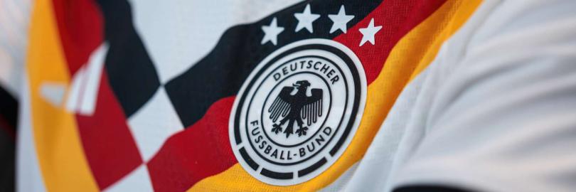 Nahaufnahme des weißen DFB-Heimtrikots für die WM 2026 mit dem runden Logo des Deutschen Fußball-Bundes und vier Weltmeister-Sternen.