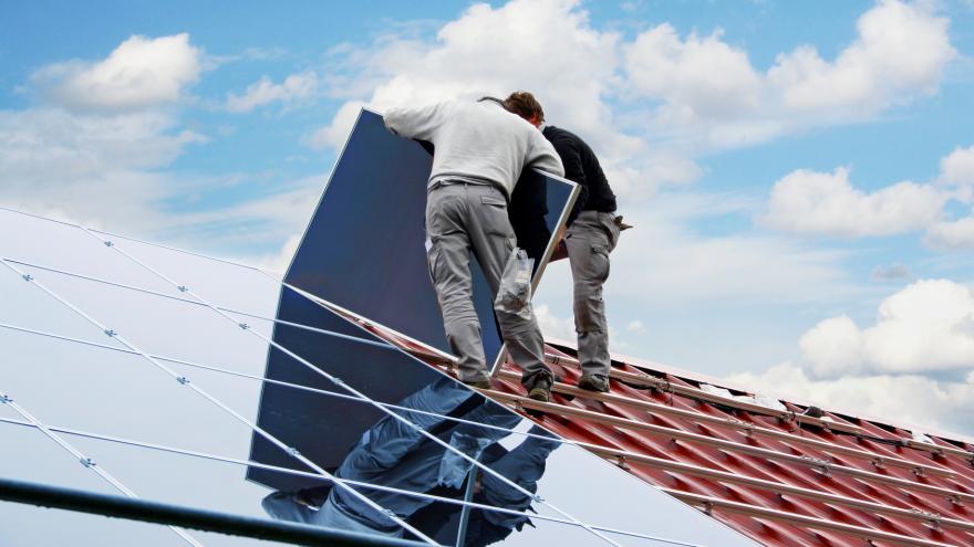 Zwei Handwerker montieren eine Solaranlage auf einem Hausdach