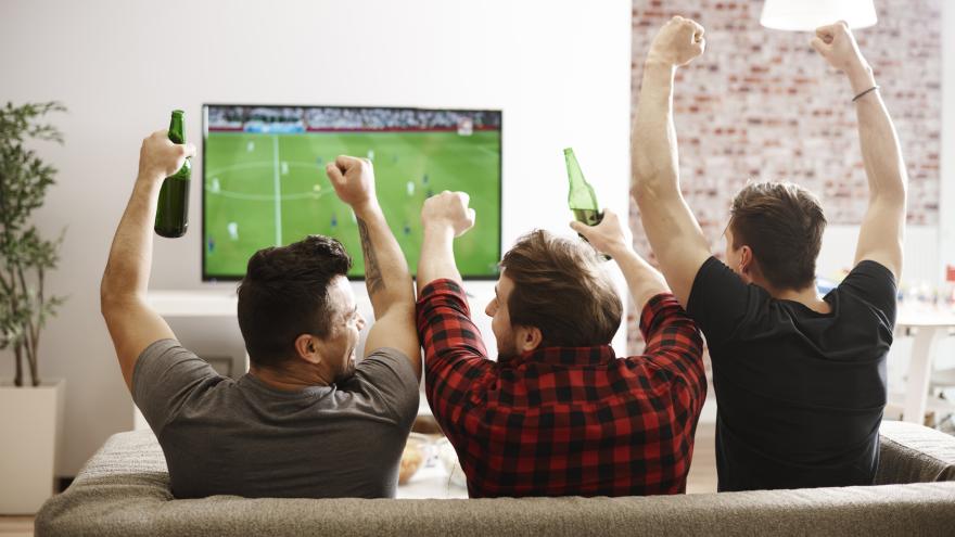 Drei Männer schauen ein Fussballspiel