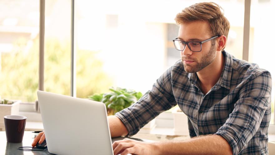 Mann sitzt vor Laptop