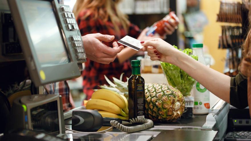 Kasse im Supermarkt, Waren auf Laufband, Kunde bezahlt