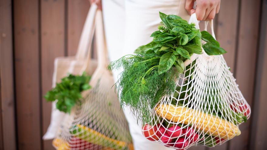 Ein Mensch trägt Netze voller Gemüse