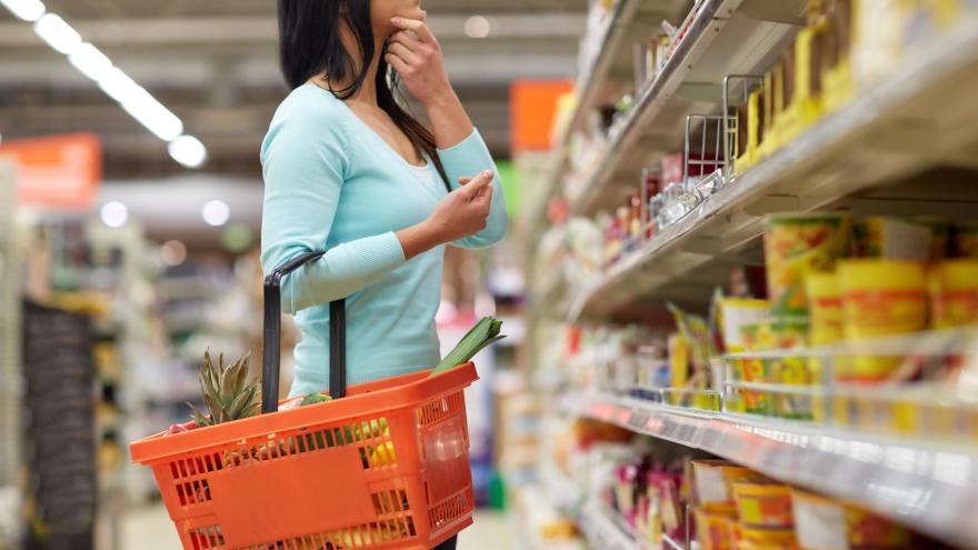 Frau steht vor Regalen im Supermarkt