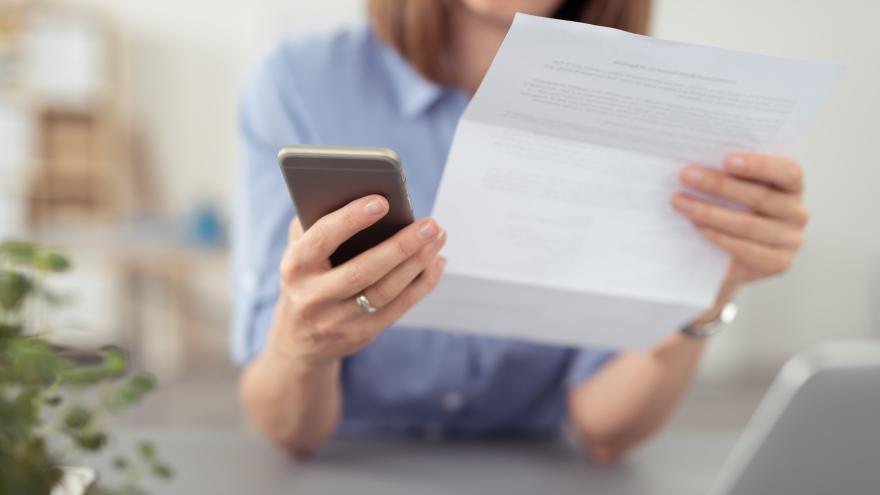 Frau liest Brief und wählt auf dem Telefon eine Nummer