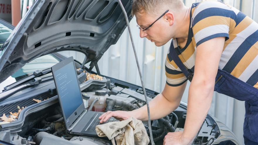 In einer Kfz-Werkstatt untersucht jemand den Motor eines Autos.