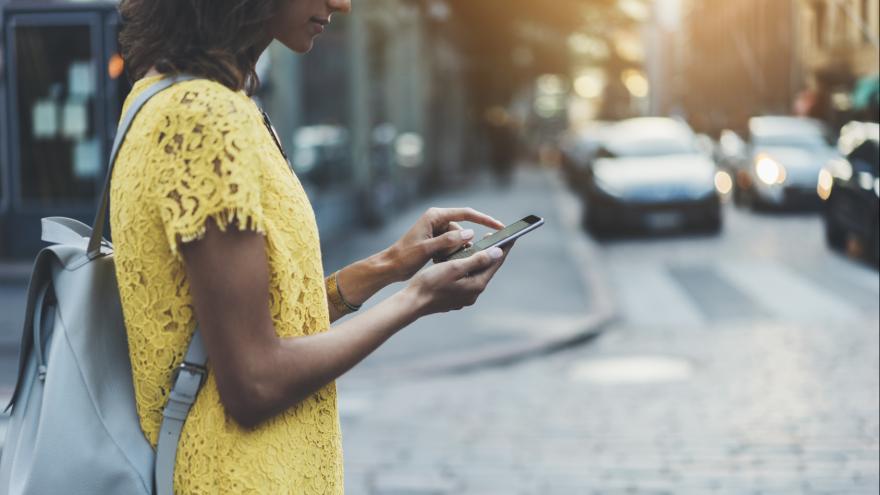 Junge Frau mit Smartphone geht in der Stadt spazieren