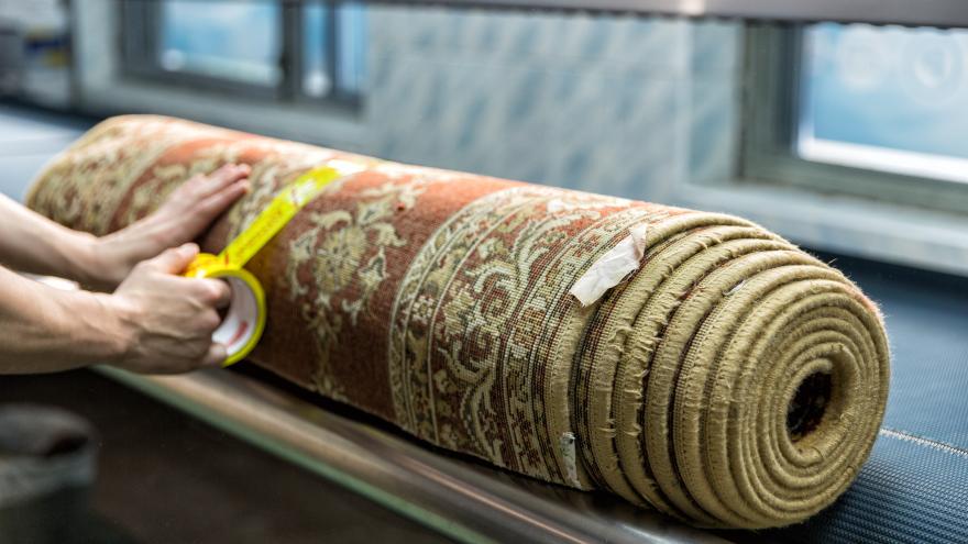 Teppich wird zusammengerollt und mit Klebeband fixiert
