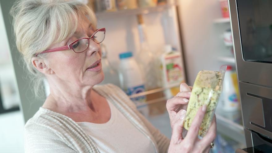 Ältere Frau überprüft Haltbarkeitsdatum eines Lebensmittels