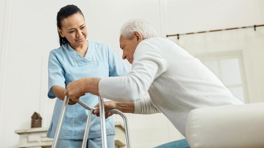 Pflegerin hilft älterem Mann beim Aufstehen