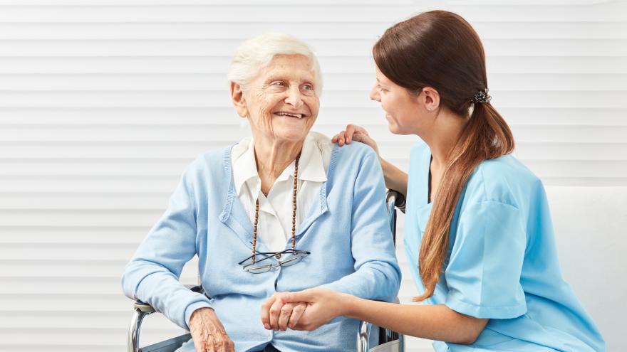 Pflegerin kümmert sich um Seniorin im Rollstuhl