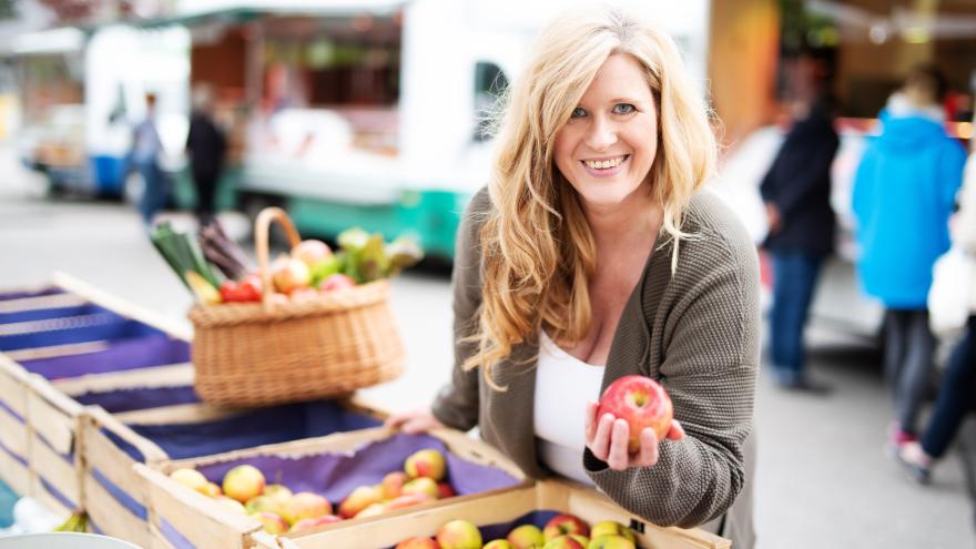 Frau sucht Apfel aus Kiste