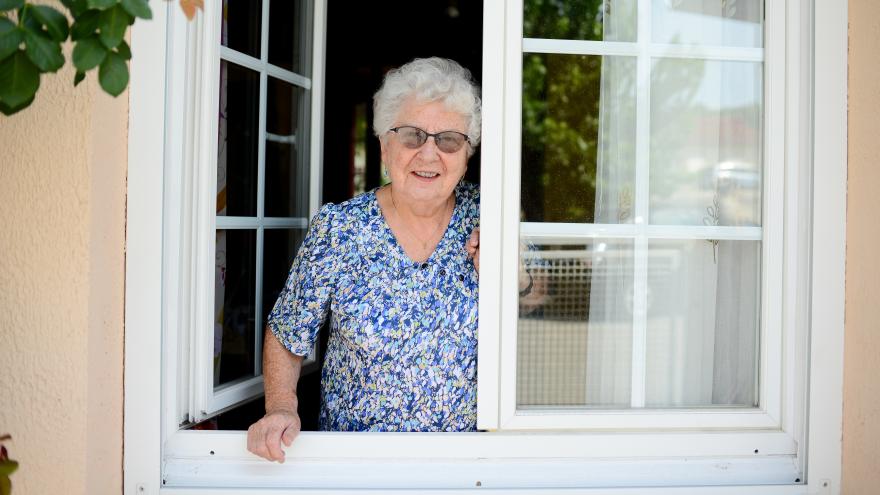 Seniorin steht am Fenster