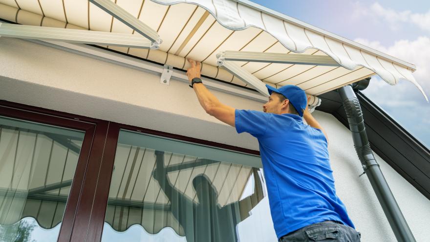 Mann installiert Markise auf Balkon