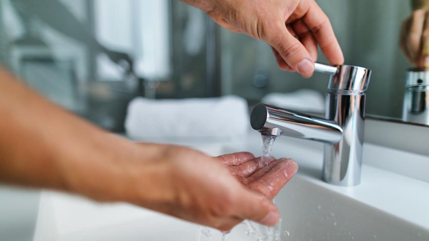 Person wäscht sich Hände unter Wasserhahn