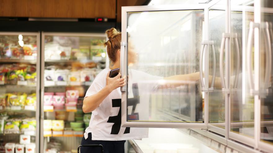 Frau steht vor Kühlregal im Supermarkt