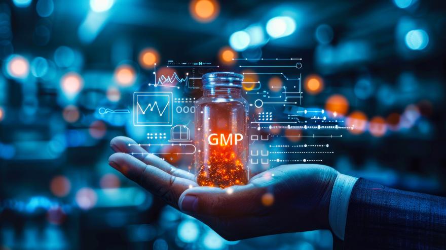 Ein Mann hält ein Glasgefäß in der Hand, auf dem die Buchstaben GMP für Good Manufacturing Process stehen