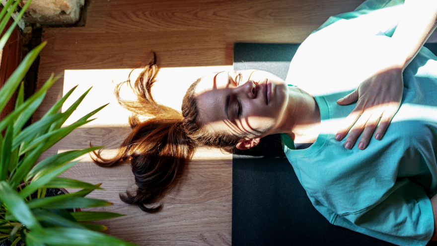 Frau liegt auf einer Matte und meditiert