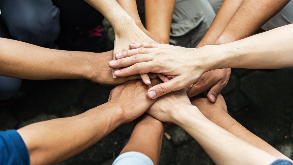 Hände übereinander im Team