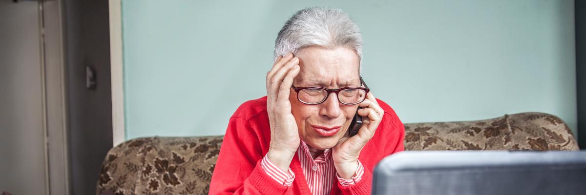 Seniorin ärgert sich am Telefon und Laptop