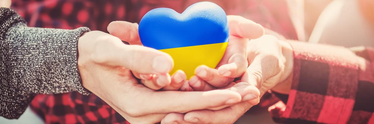 Hände halten ein Herz in den ukrainischen Farben blau und gelb