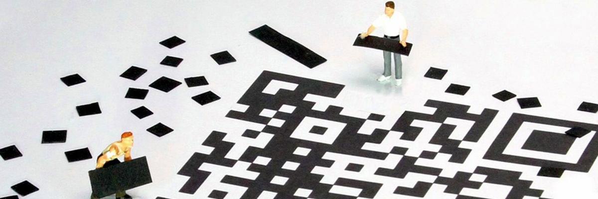 Miniaturfiguren bauen aus kleinen Papierschnipseln einen QR-Code
