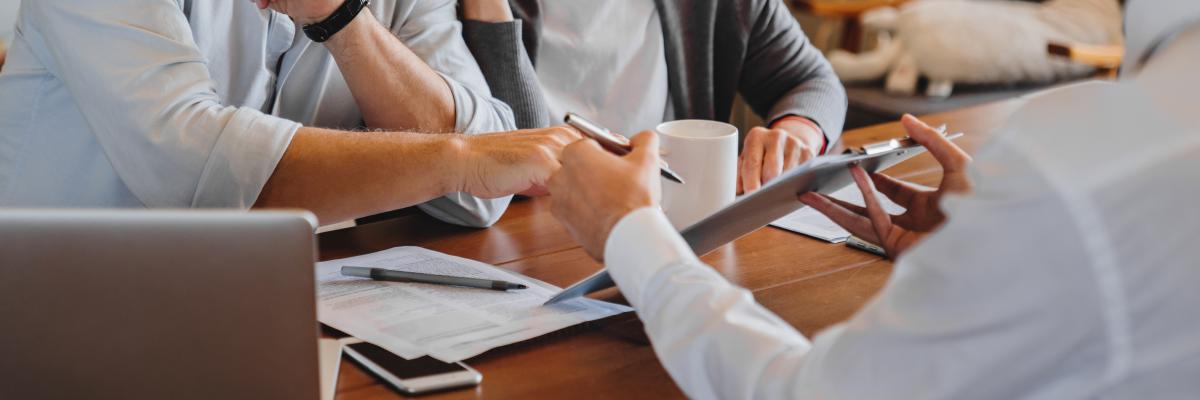 älteres Paar lässt sich von Berater etwas auf dem Tablet zeigen