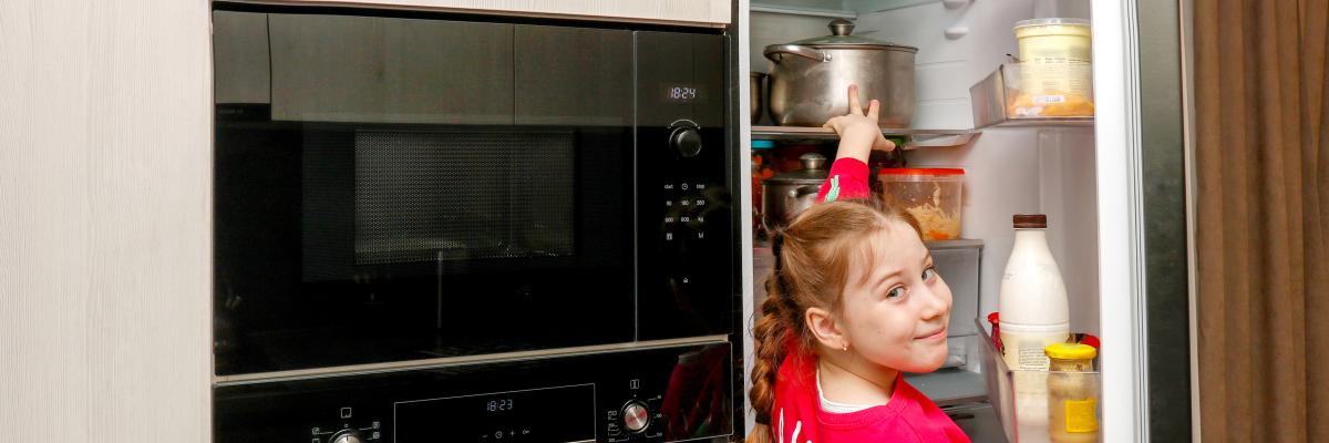 Kind macht Kühlschrank auf