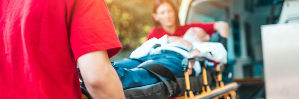 Zwei Sanitäter schieben eine Bare mit einem Patienten in einen Krankenwagen