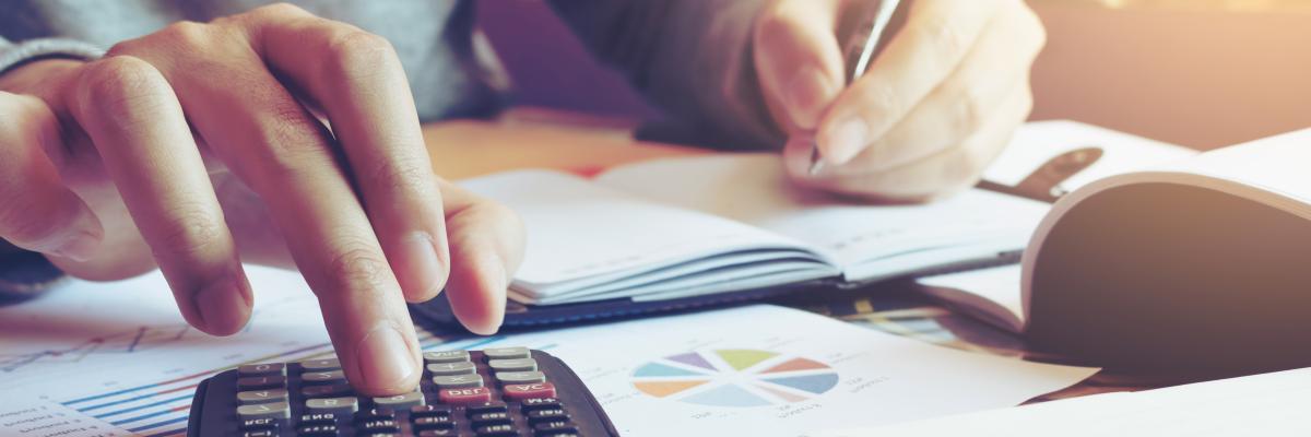 Hände mit Stift und Taschenrechner