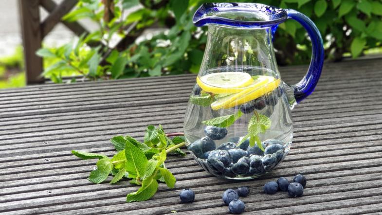 Karaffe gefüllt mit Wasser, Blaubeeren, Zitronenscheiben und Minzblättern