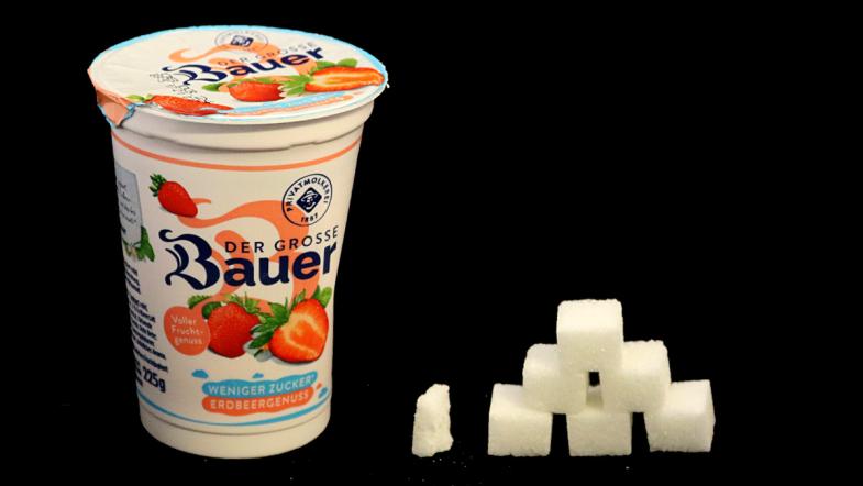 Joghurtbecher von Bauer und daneben eine Zuckerwürfel-Pyramide