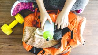 Fitnessstudio - Frau packt ihre Trinkflasche in die Tasche