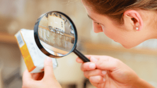 Verpackung wird mit Lupe betrachtet
