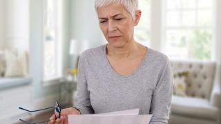 Frau schaut skeptisch auf ein Schreiben