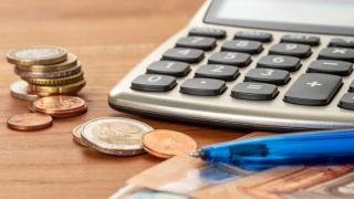 Geldmünzen vor Taschenrechner und Stift