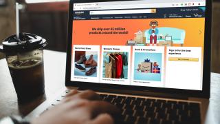 Person sitzt am Laptop und halt Amazon-Seite geöffnet
