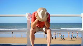 Mann stützt sich den Kopf auf die Hände am Strand