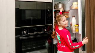 Kind macht Kühlschrank auf